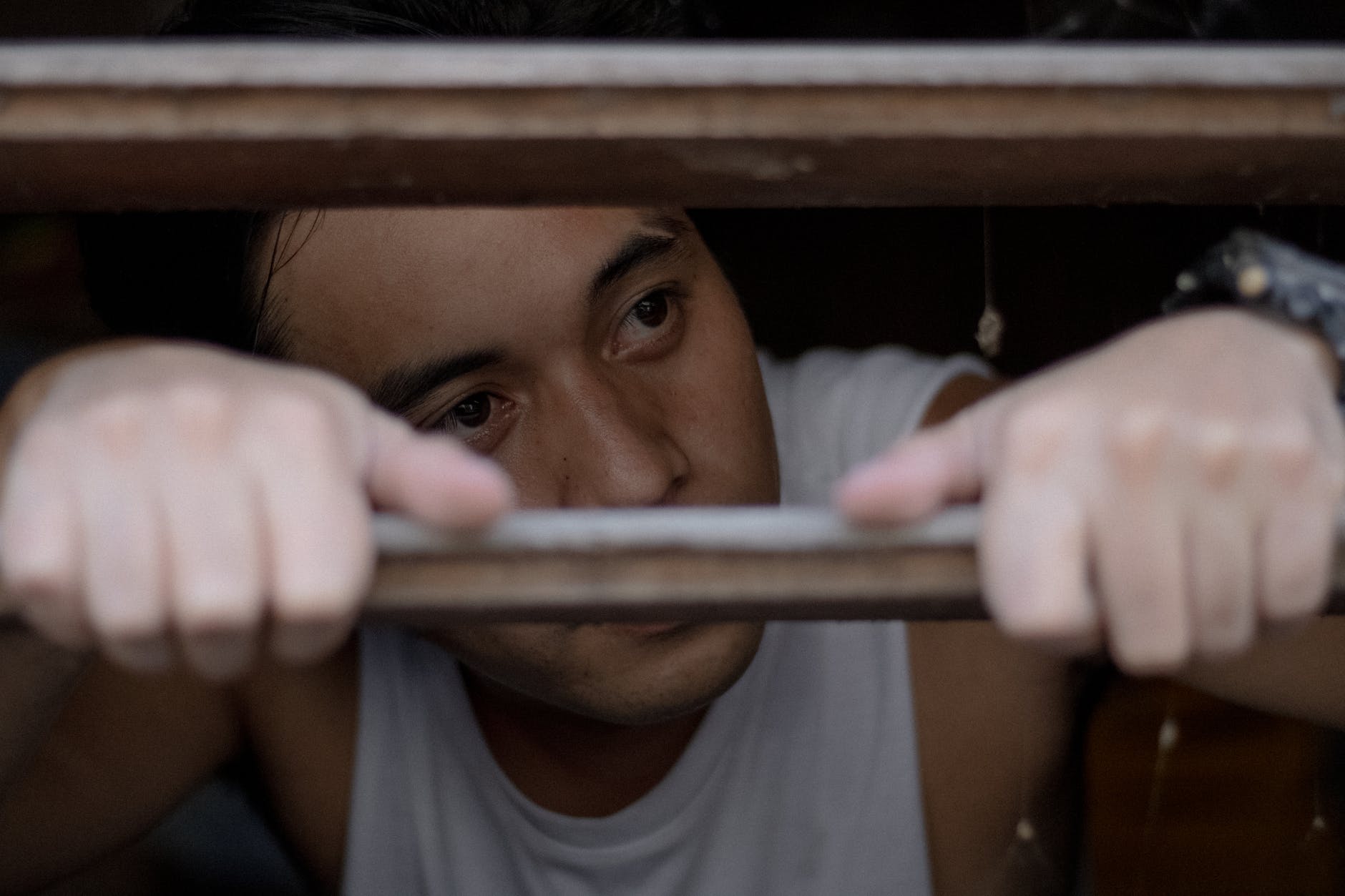 crop pensive ethnic man behind bars in daytime